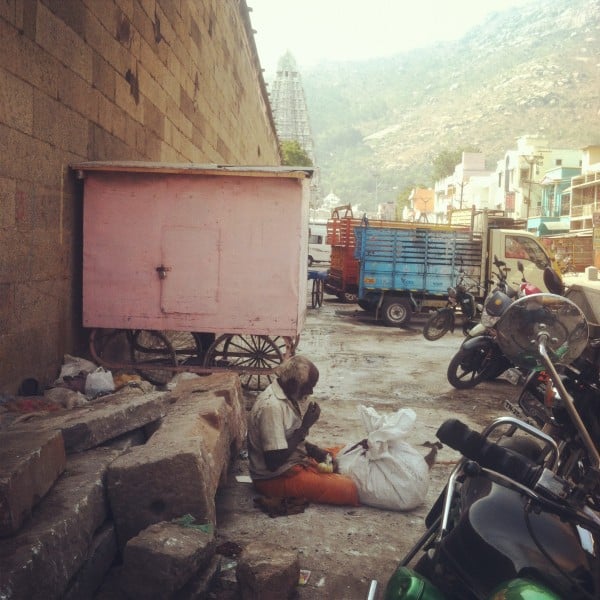 A homeless man. His backdrop is the ancient temple and the holy mountain. Real life.