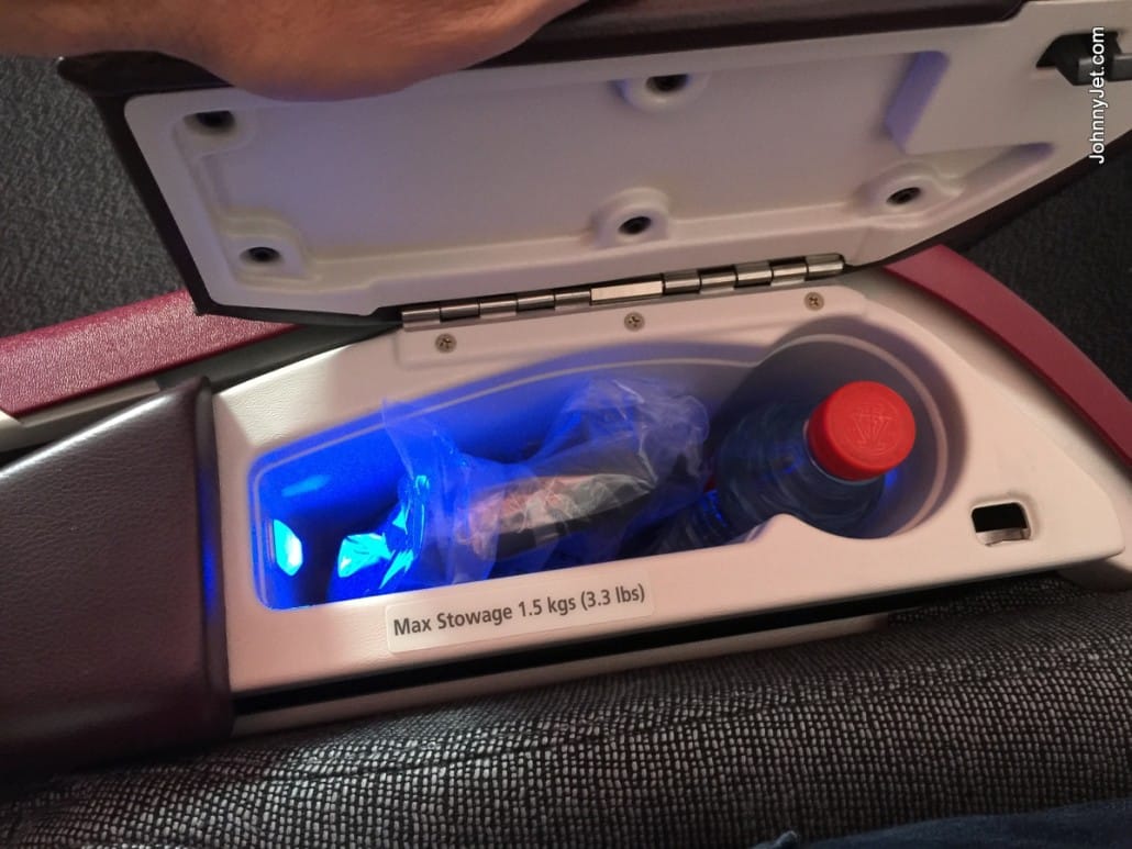 Business Class compartment with headphones and a bottle of water on Qatar Airways A380