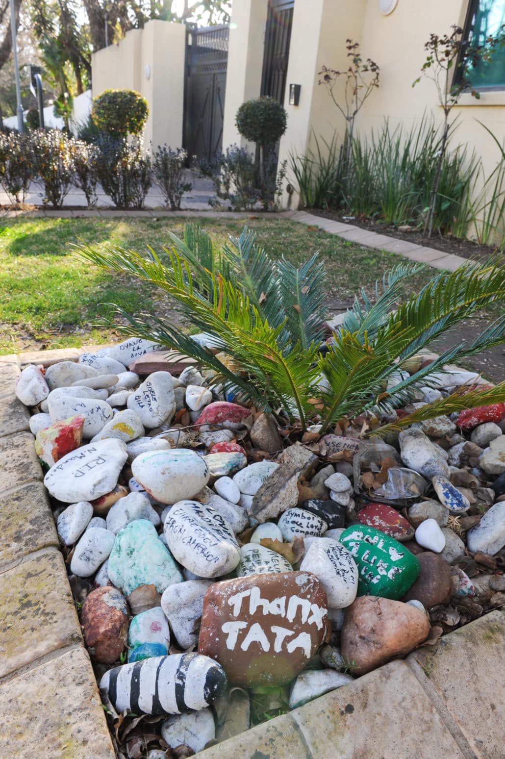 In front of Nelson Mandela's former residence, visitors leave personalized good will messages on stones which are left out front